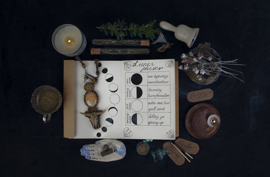 Book of Shadows with lunar phases on black altar. 