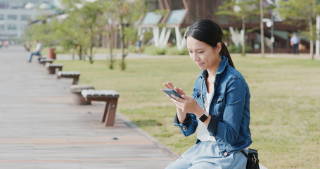 Woman look at mobile phone in the city park