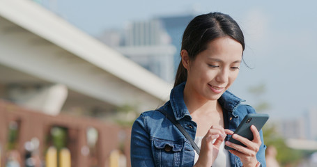 Woman look at smart phone in the city park