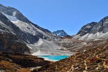 Unique colored Milk lake (approx. 4300m altitude) with blue sky and sharp mountains around it in Daocheng Yading Nature Reserve, Sichuan, China.  