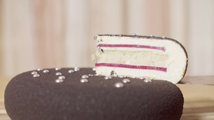 Close up knife taking out the piece of cake with silver droplets - obrazy, fototapety, plakaty
