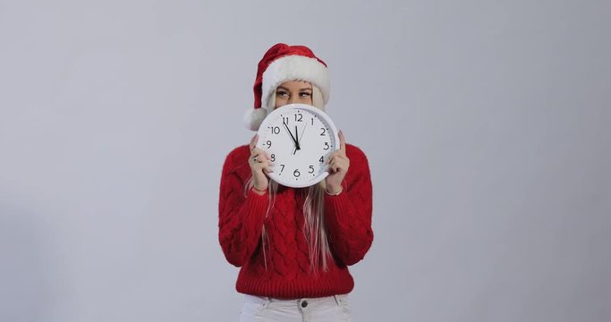 Late new year and christmas shopping girl with big wall clock in santa claus hat on white background