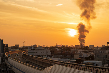 Osaka, Japan - December 2, 2018: Fire burns in Suita City billowing dark smoke into sky as sun sets