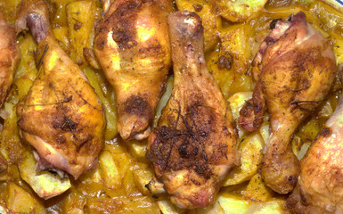 Detail of chicken with potatoes in oven, from up, flat view