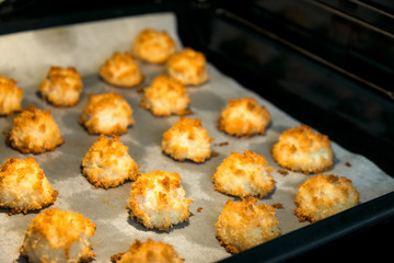 Christmas coconut puffs macaroon cookies on parchment paper on tray in oven. Festive cozy home atmosphere. Holiday pastry baking concept. Italian French cuisine