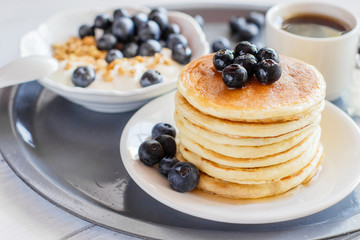 Delicious and healthy breakfast of pancakes with blueberries, granola and a cup of coffee