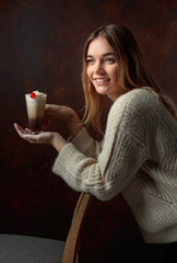 Beautiful blonde in a sweater holding a mug of coffee with cream.