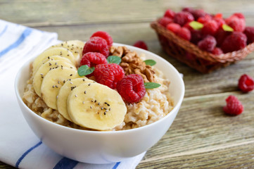 Delicious and healthy oatmeal with banana, raspberries, nuts. Healthy breakfast. Fitness food. Proper nutrition.