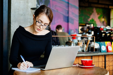 pretty young beautiful woman in glasses using laptop in cafe, close up portrait of business woman, a computer, financial analyst, a sales manager, prepares a report, charts.