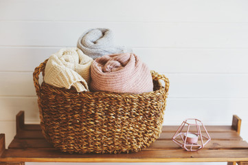 cozy interior details, scandinavian mininalistic lifestyle. Organizing clothes in wicker backets,...