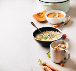 Pea, tomato, vegetable soups and ingredients on concrete background