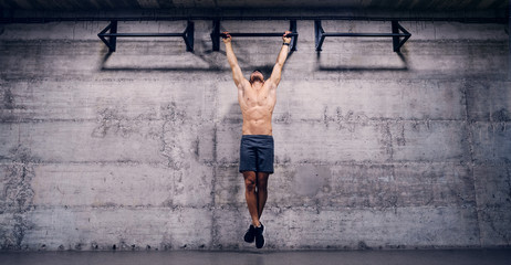 Shirtless man doing pull ups in the gym. When you lose all excuses, you'll find results.