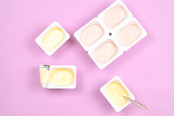 Plastic cup with tasty yogurt on lilac background. Top view. Space for text or design.