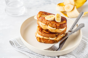 French toasts with peanut butter and banana on a white plate.