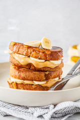 French toasts with peanut butter and banana on a white plate.
