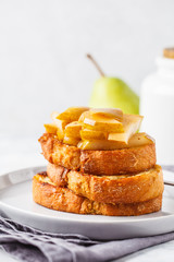 French toast with caramelized pear and syrup on a gray background.