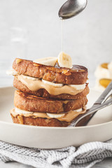 French toasts with peanut butter and banana on a white plate.