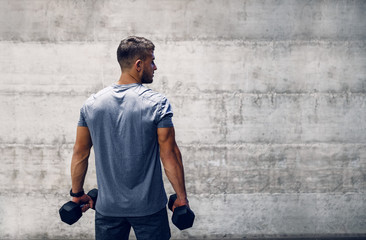 Man holding dumbbells while standing with backs turned. Fit is not destination, it is a way of life.