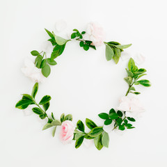 Floral round frame of roses and green leaves on white background. Flat lay, top view. Spring time composition