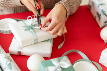 DIY Gift Wrapping. Unrecognisable woman wrapping beautiful nordic style christmas gifts. Hands close up.