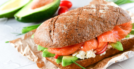 sandwich with avocado and salmon on a light background, green onions and gluten-free grain bread, radishes and tomatoes. concept diet food, copy space, sandwich take away, healthy fast food - Powered by Adobe
