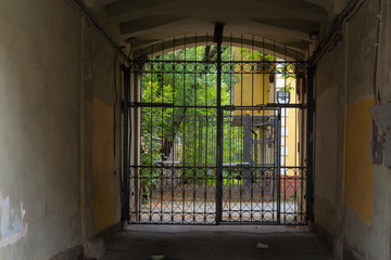 Dark arch with grille in front of a cozy courtyard