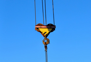 Hook gantry crane on the chain for lifting heavy loads on the background of a metal beam and a blue...