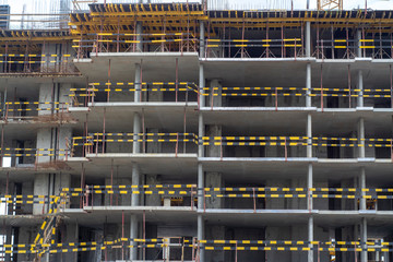 Unfinished building with protective fences in view of black and yellow stripes on the facade
