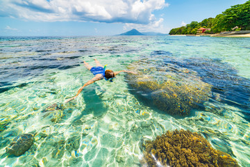 Woman snorkeling on coral reef tropical caribbean sea, turquoise blue water. Indonesia Banda archipelago, Moluccas Maluku, tourist diving travel destination