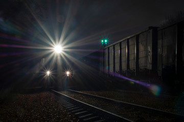 A locomotive with lights on is standing at night on the railway preparing for the departure