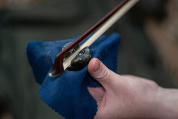 The girl rubs the bow of the violin with rosin before the game