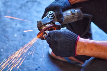 Worker cutting metal with grinder.