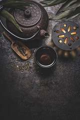 Black iron asian tea set on dark rustic background with teapot and fresh tea leaves, top view with copy space for your design. Authentic vintage style