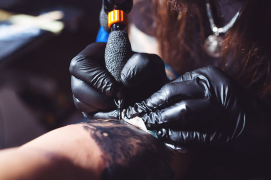 Professional tattoo artist makes a tattoo on a man's hand