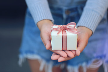 Selective focus of Woman hands holding yellow gift box with pink ribbon for Christmas and New Year's Day or Greeting season, Valentines day