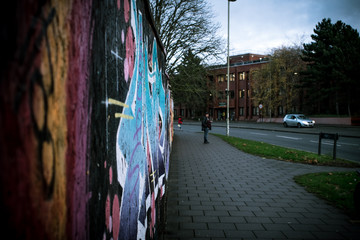 Graffiti wall in english town with pedestrian in background