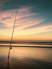 Fishing rod in sand at sunset over the Atlantic Ocean, Agadir, Morocco 