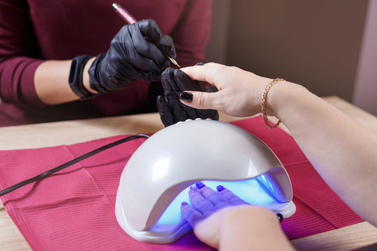 professional nail art and manicure salon, painting and drying nails in UV lamp dryer