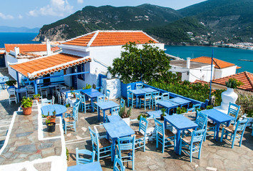 An old restaurant on hill in Skopelos town with outdoor seats from woodware blue painted furnitures and sea views