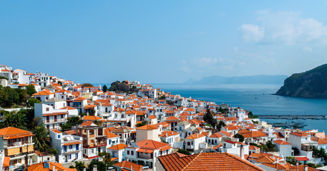 Summer day panoramic view from hill on old Skopelos town with traditional greek white walls buildings and orange tile roofs