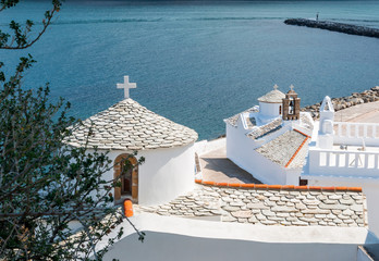 The white Church Panagitsa of Pyrgos with stone tile on Skopelos island against the blue sea of city bay