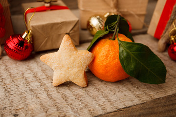 Gingerbread cookie star and tangerine with Christmas decoration on vintage wooden background. Christmas new year closeup