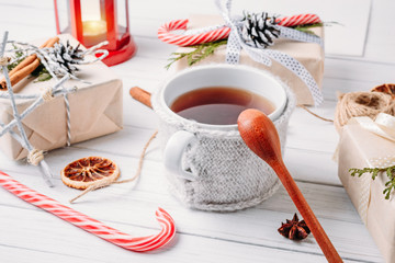Christmas decorations with gift boxes, pine cones and a cup of tea on white wooden background. Cozy home
