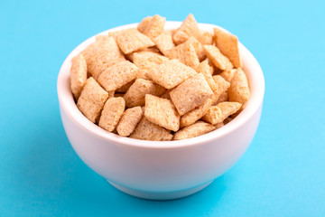 Crunchy corn pads in clay bowl on bright blue background