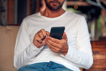 Man sitting on a terrace sofa and using cellphone.