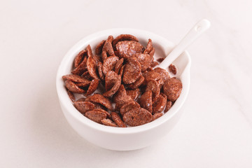 Crunchy chocolate corn flakes in bowl with milk