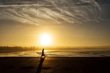 Man enjoying the beauty of sunrise in Essaouira, Morocco. WIth the ocean and beautiful clouds in background