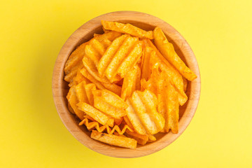 Crispy corrugated potato chips in wooden bowl