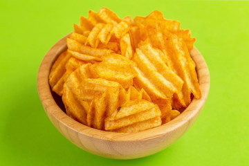 Crispy corrugated potato chips in wooden bowl