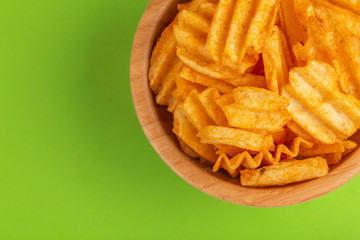 Crispy corrugated potato chips in wooden bowl